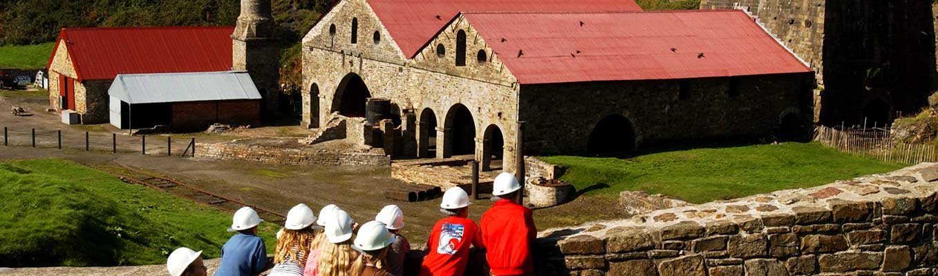 Blaenavon Ironworks - school children wearing hard hats looking at ironwork buildings